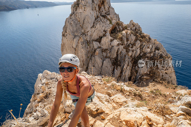 费拉塔岛(Via Ferrata)上的攀登者，年轻的妇女们在攀登海面上的岩石